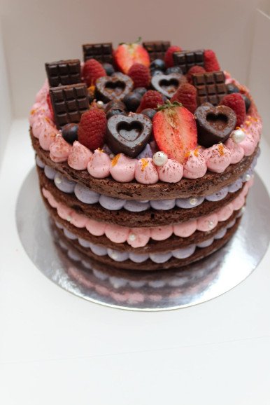 Naked chocolate cake topped with homemade chocolates and fruit