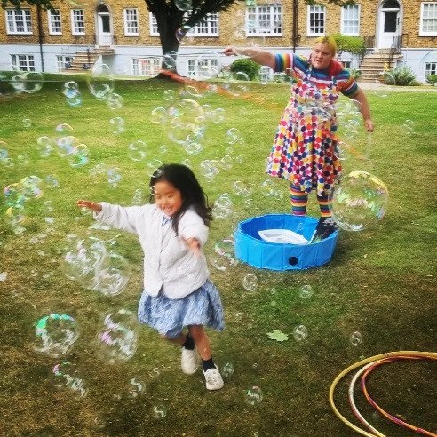 Children chasing hundreds of rainbow bubbles in a park